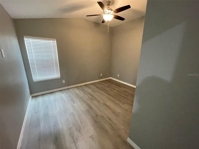 empty room with lofted ceiling, ceiling fan, and light wood-type flooring