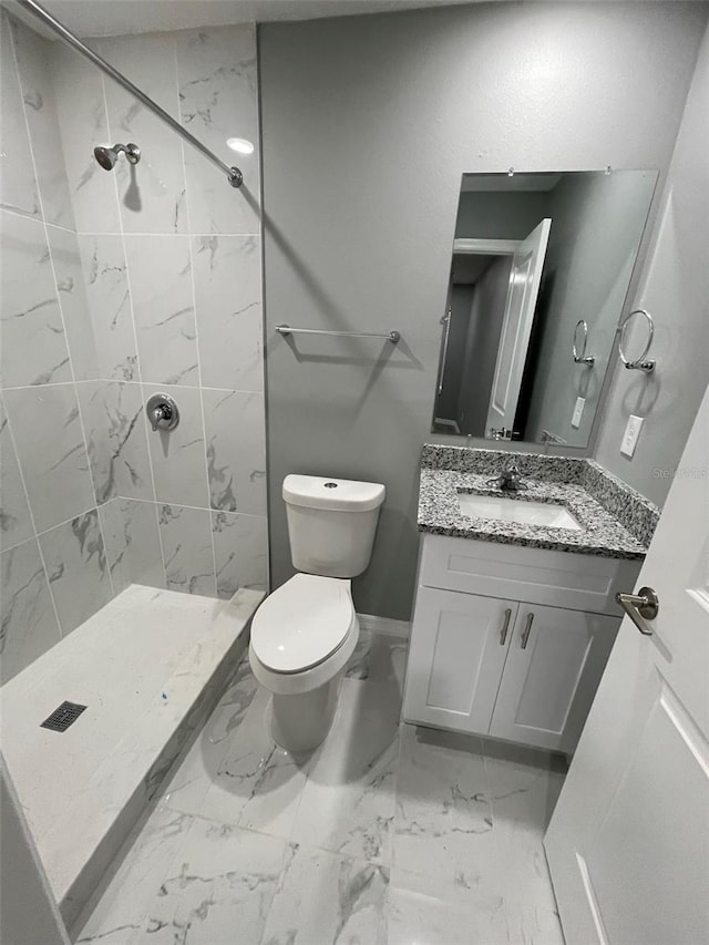 bathroom with vanity, toilet, and a tile shower