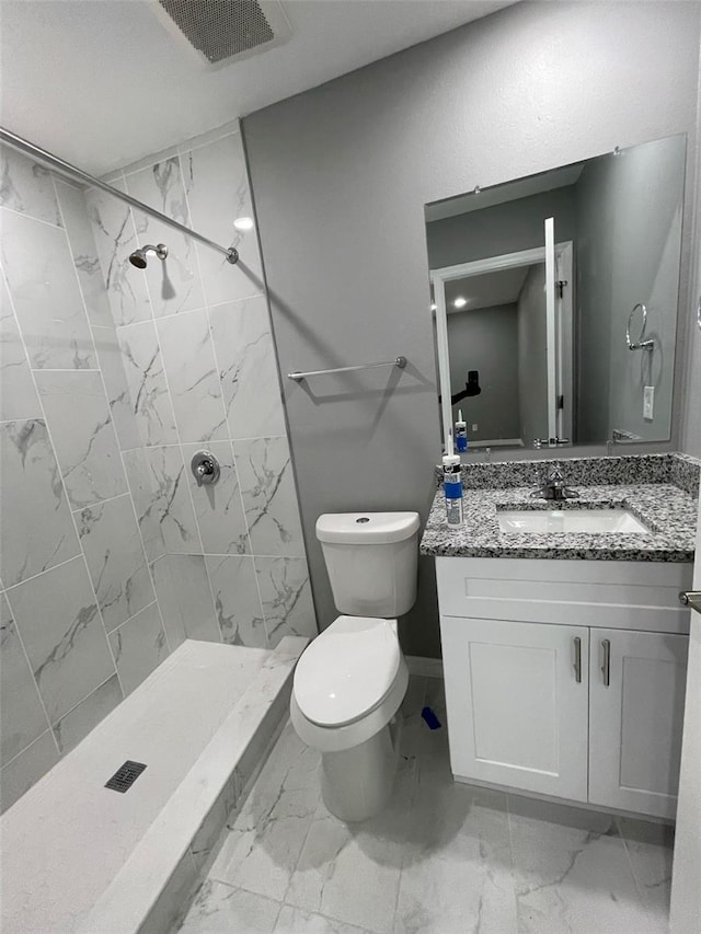 bathroom with vanity, toilet, and a tile shower