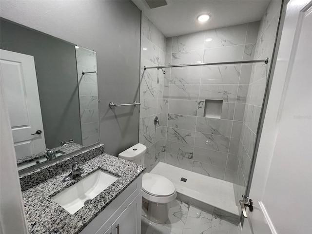 bathroom with vanity, toilet, and tiled shower