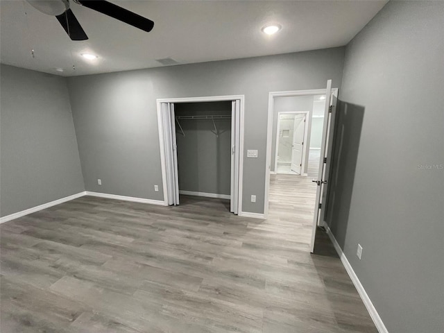 unfurnished bedroom featuring ceiling fan, light hardwood / wood-style floors, and a closet