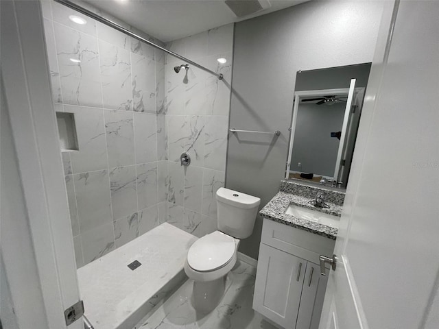 bathroom with a tile shower, vanity, and toilet