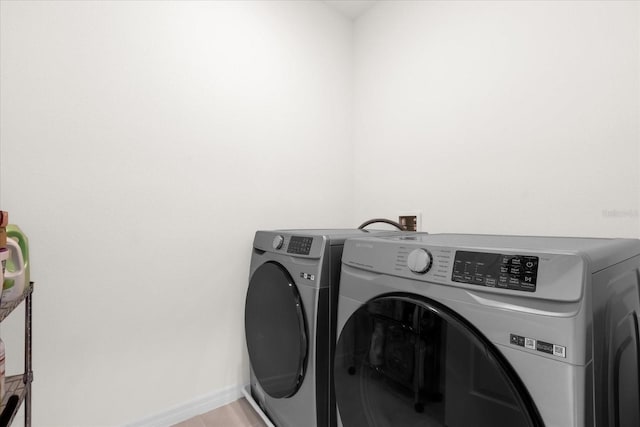 washroom featuring laundry area, washing machine and dryer, and baseboards