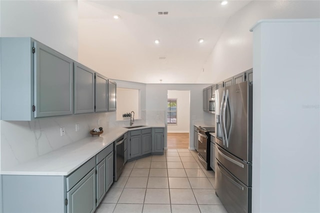 kitchen featuring tasteful backsplash, stainless steel appliances, sink, light tile patterned floors, and gray cabinets