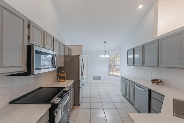 kitchen with gray cabinetry, hanging light fixtures, stainless steel appliances, a notable chandelier, and light tile patterned floors