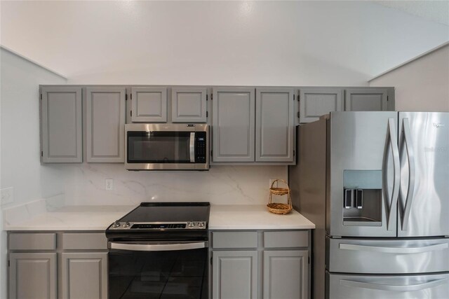 kitchen with gray cabinetry, decorative backsplash, and appliances with stainless steel finishes