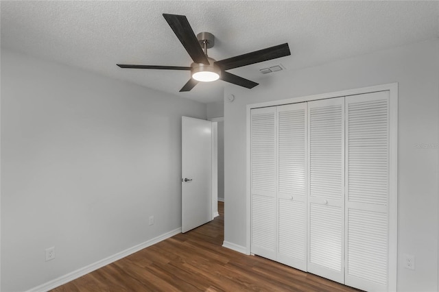 unfurnished bedroom with ceiling fan, dark hardwood / wood-style floors, a textured ceiling, and a closet