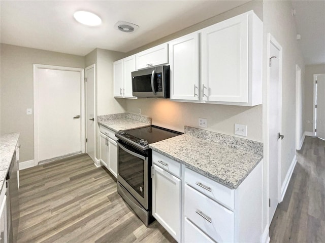 kitchen featuring white cabinetry, light hardwood / wood-style floors, light stone counters, and appliances with stainless steel finishes