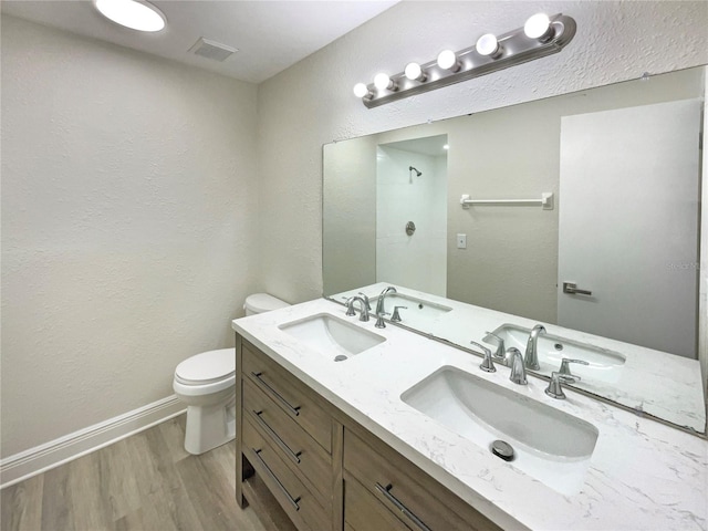 bathroom with hardwood / wood-style flooring, vanity, toilet, and a shower