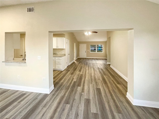 unfurnished living room with dark hardwood / wood-style floors, ceiling fan, and vaulted ceiling