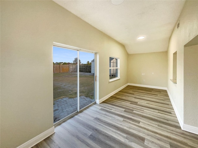 unfurnished room with light wood-type flooring and lofted ceiling