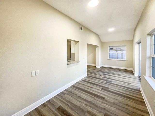 spare room featuring dark hardwood / wood-style flooring and vaulted ceiling