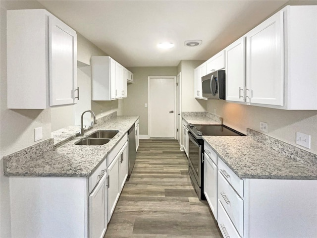 kitchen featuring light stone countertops, sink, light hardwood / wood-style floors, white cabinets, and appliances with stainless steel finishes