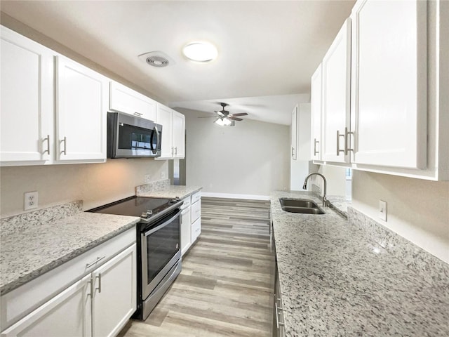 kitchen featuring light stone countertops, sink, appliances with stainless steel finishes, white cabinets, and light wood-type flooring