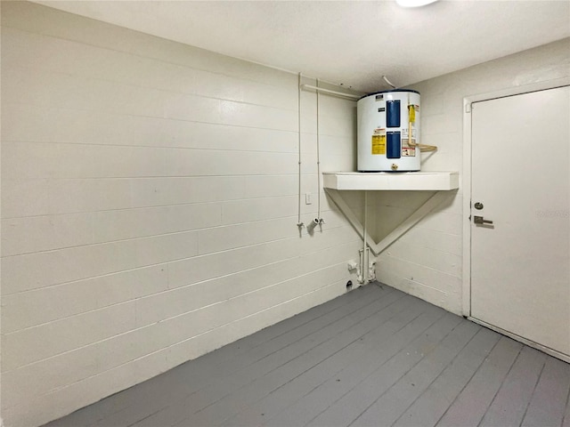 clothes washing area featuring hardwood / wood-style flooring and water heater