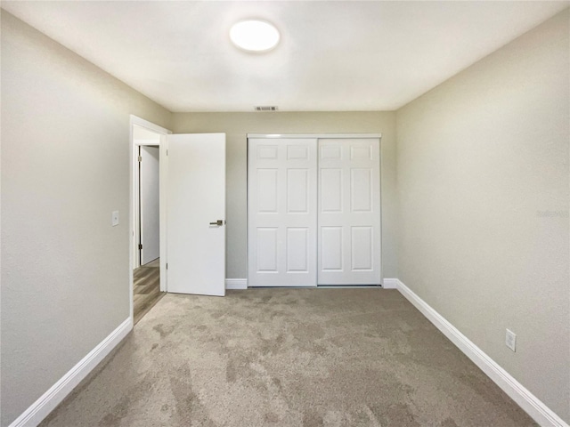 unfurnished bedroom featuring light carpet and a closet