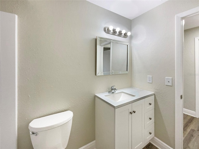 bathroom with hardwood / wood-style floors, vanity, and toilet