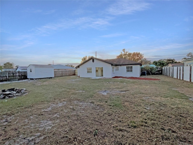 rear view of property featuring a lawn and a storage shed