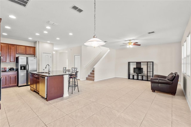 kitchen featuring a kitchen island with sink, a kitchen breakfast bar, sink, ceiling fan, and stainless steel appliances