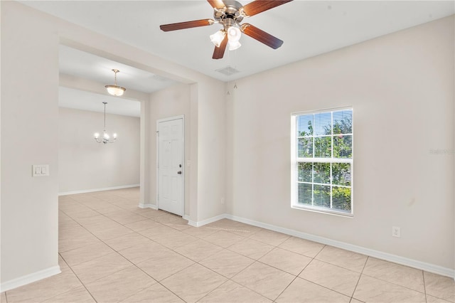 tiled empty room with ceiling fan with notable chandelier