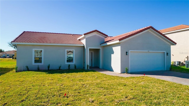 mediterranean / spanish house featuring cooling unit, a garage, and a front lawn