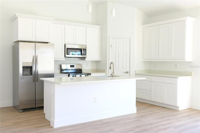 kitchen with a kitchen island with sink, white cabinetry, sink, and stainless steel appliances