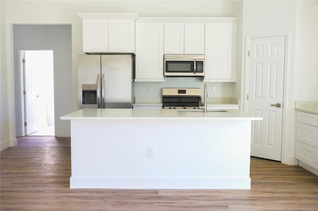 kitchen featuring appliances with stainless steel finishes, a center island with sink, white cabinetry, and wood-type flooring