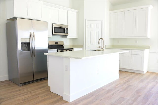 kitchen with sink, light hardwood / wood-style flooring, a kitchen island with sink, white cabinets, and appliances with stainless steel finishes