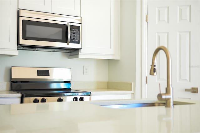 kitchen featuring white cabinets, range, and sink