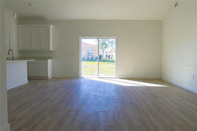 unfurnished living room featuring dark hardwood / wood-style floors, lofted ceiling, and sink