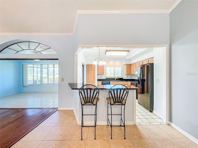 kitchen with kitchen peninsula, crown molding, black appliances, and light hardwood / wood-style floors