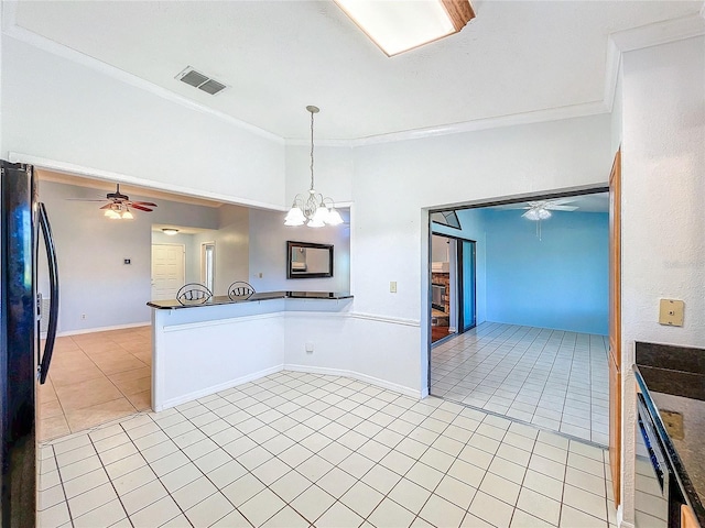 kitchen featuring black refrigerator, ornamental molding, ceiling fan with notable chandelier, pendant lighting, and light tile patterned floors