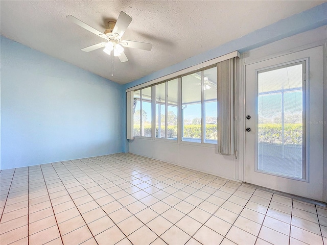 empty room with ceiling fan, light tile patterned floors, a textured ceiling, and a wealth of natural light