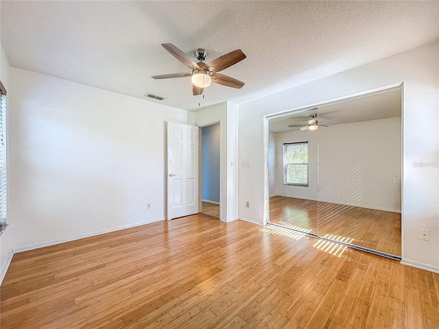 unfurnished room with a textured ceiling, light hardwood / wood-style flooring, and ceiling fan