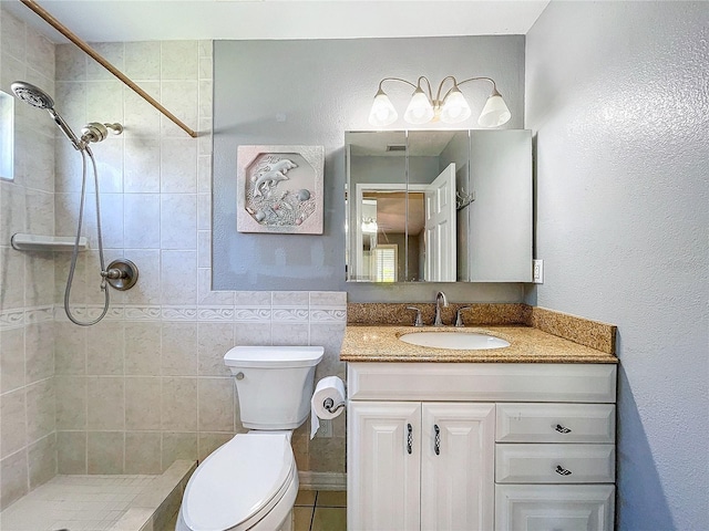 bathroom featuring tiled shower, tile patterned floors, vanity, and toilet