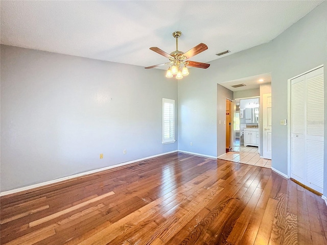 empty room with ceiling fan, light hardwood / wood-style flooring, and a textured ceiling