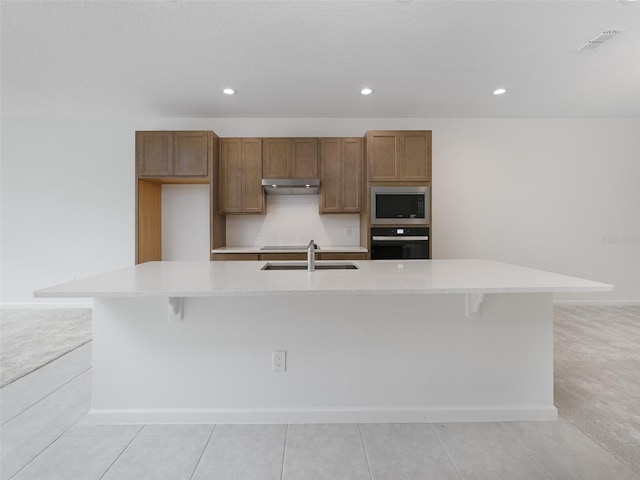 kitchen featuring appliances with stainless steel finishes, sink, light carpet, and a large island with sink