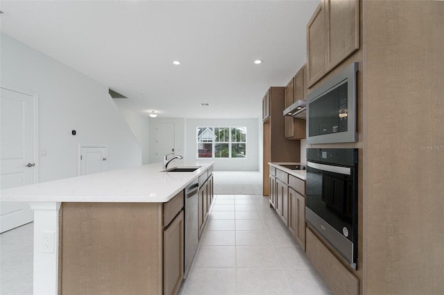 kitchen featuring light tile patterned floors, stainless steel appliances, a kitchen island with sink, and sink