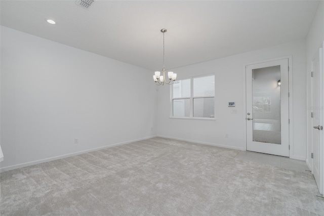 empty room with light carpet and a chandelier