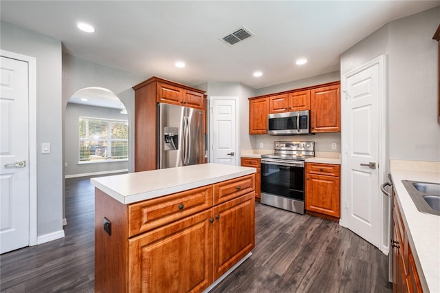 kitchen featuring stainless steel appliances, a kitchen island, dark wood-type flooring, and sink