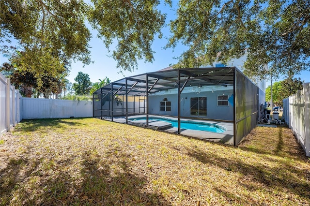 rear view of house with a lanai, a fenced in pool, and a yard