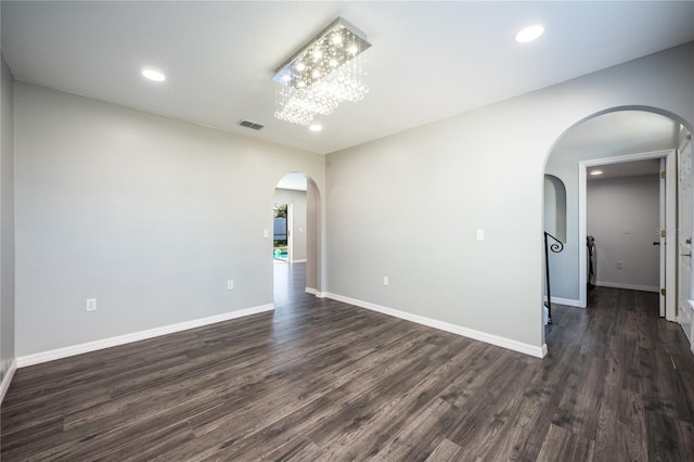 empty room featuring a notable chandelier and dark hardwood / wood-style flooring