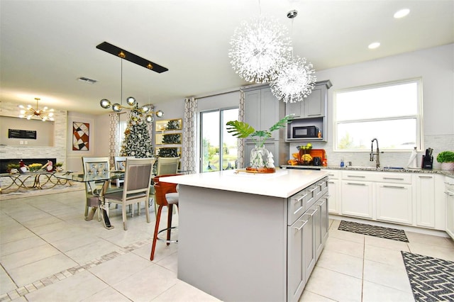 kitchen featuring sink, a notable chandelier, decorative light fixtures, gray cabinets, and a kitchen island