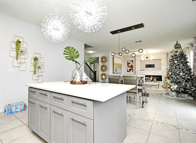 kitchen with decorative light fixtures, gray cabinets, a kitchen island, and a notable chandelier