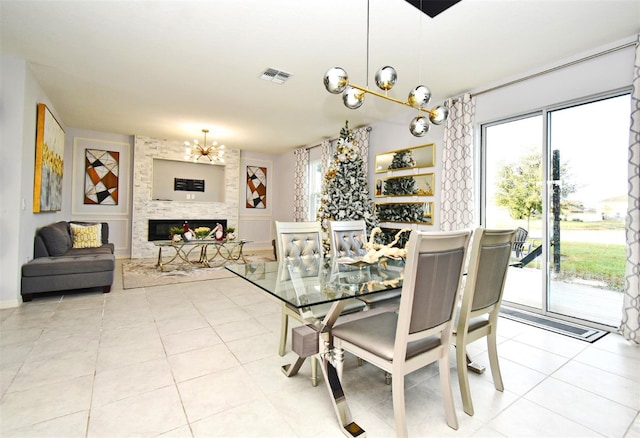 tiled dining area featuring a fireplace and a notable chandelier