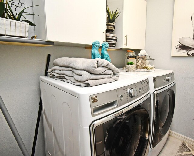 laundry room featuring cabinets, independent washer and dryer, and light tile patterned floors