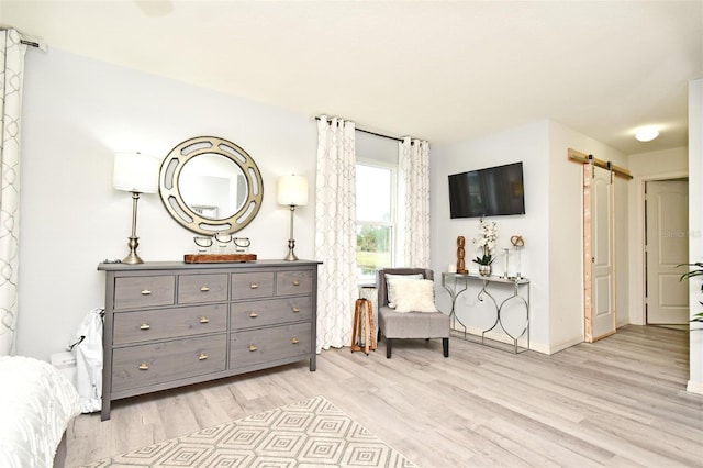 sitting room with a barn door and light hardwood / wood-style floors