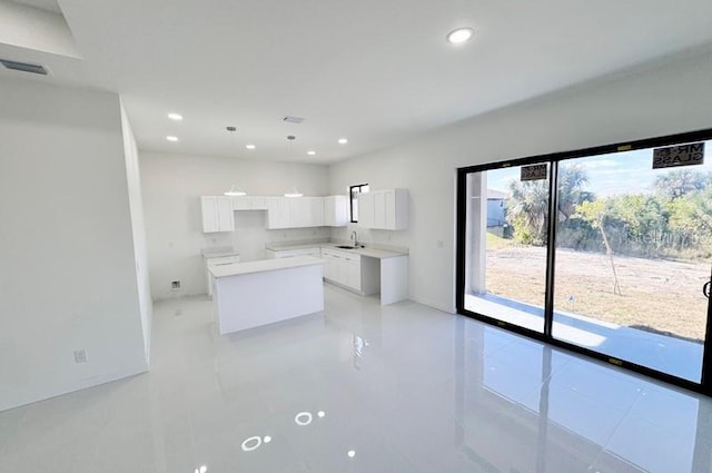 kitchen with light tile patterned floors, a center island, white cabinetry, and sink