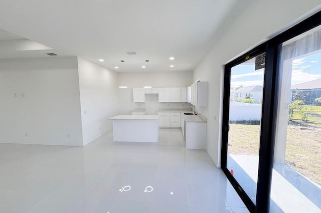 kitchen with white cabinets, a center island, light tile patterned flooring, and sink