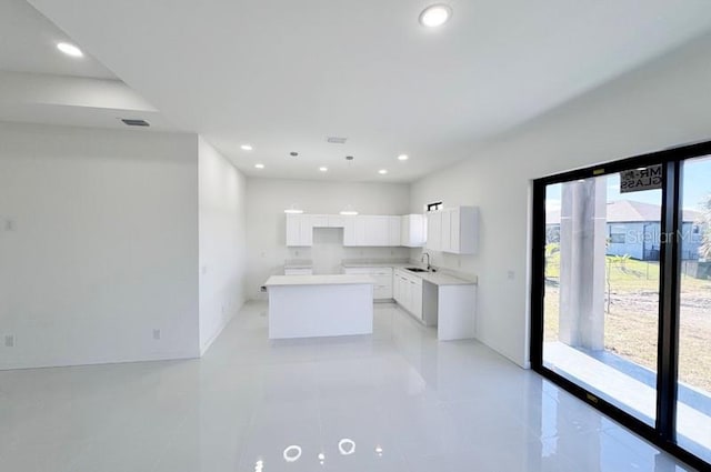 kitchen with a kitchen island, white cabinetry, and sink